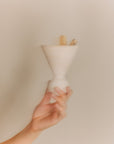 Cone Räuchergefäß aus beigefarbenem Travertinstein mit 2 Palo Santo Sticks wird von einer Hand gehalten